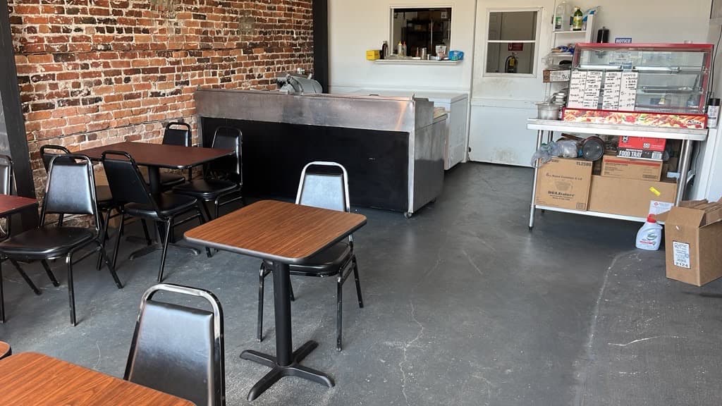 The stainless deli counter and hot food case with dining tables in the foreground.