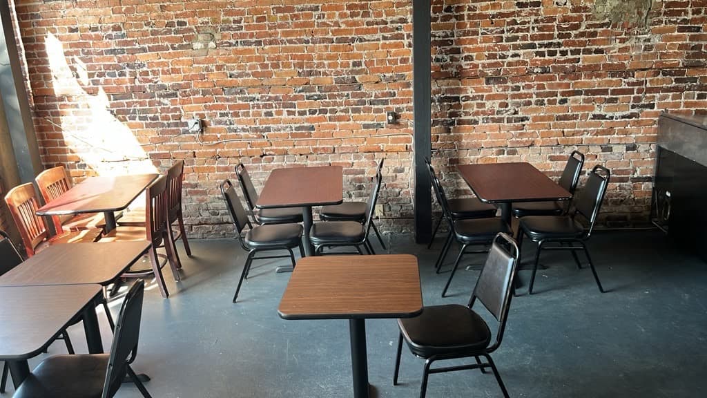 Dining tables and chairs against the exposed brick wall of the seating area.
